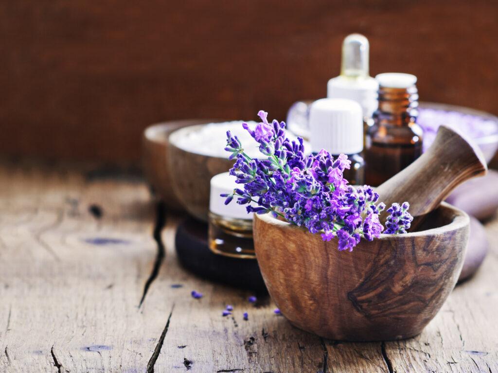 Lavendelbad, Lavendelblütenstrauß, ätherisches Öl und Salz auf einem rustikalen Holzhintergrund.