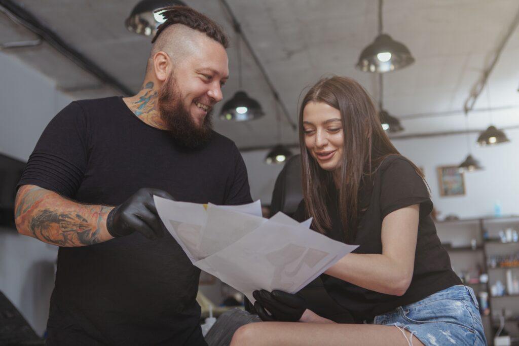 Ein Tätowierer und eine Kunden reden über ein Tattoo Motiv