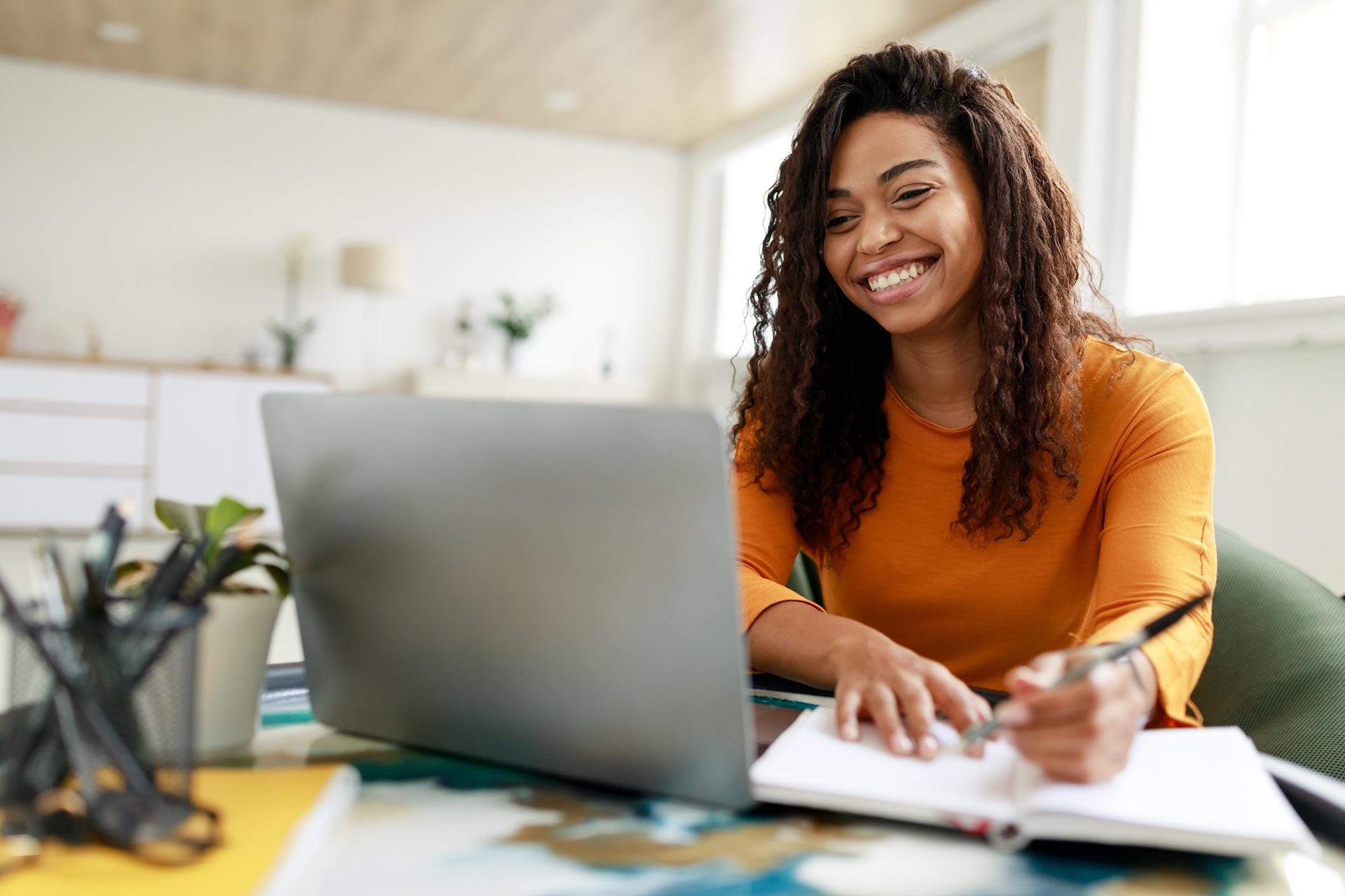 Frau lernt online mit Laptop und Notizbuch | E-Learning Anbieter